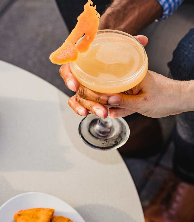 closeup of an orange cocktail with orange peel garnishing