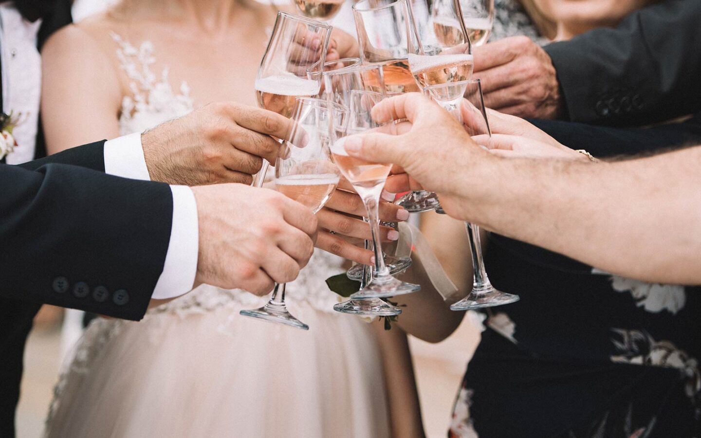 bride and groom with friends clinking champagne glasses